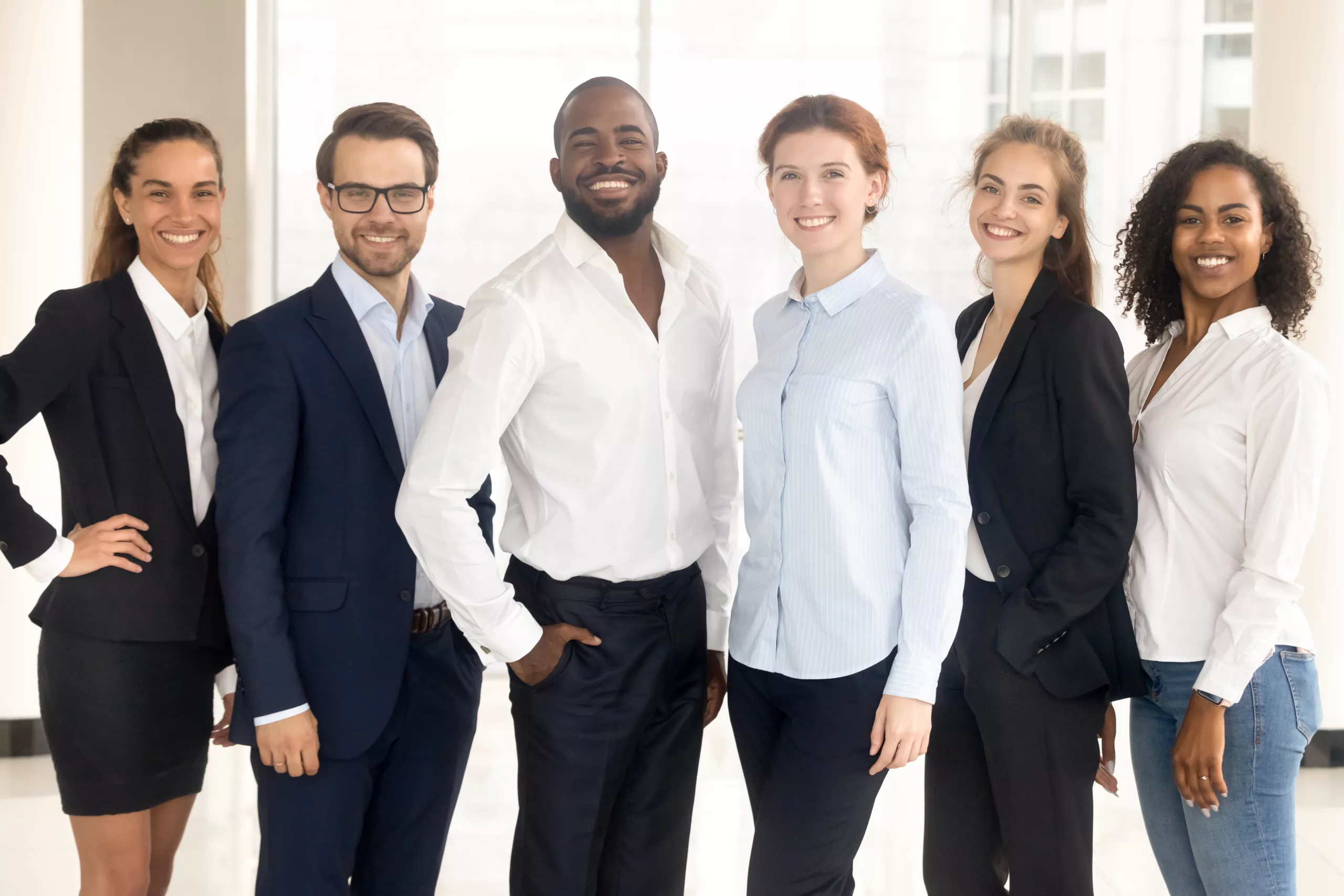 Happy diverse and multiracial employees group looking at camera. Smiling mixed race company colleagues stand together at office, business people managers portrait.